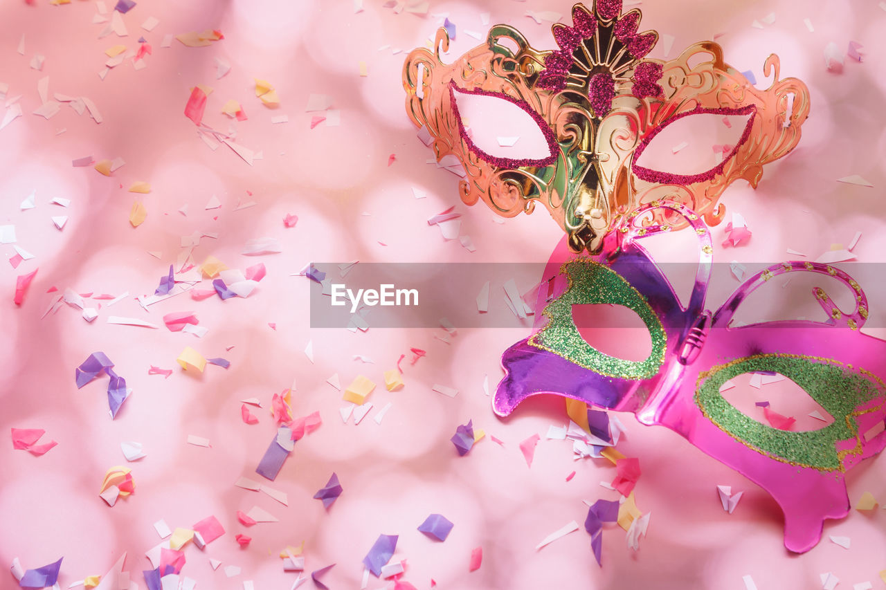 Close-up of multi colored masks and confetti on table
