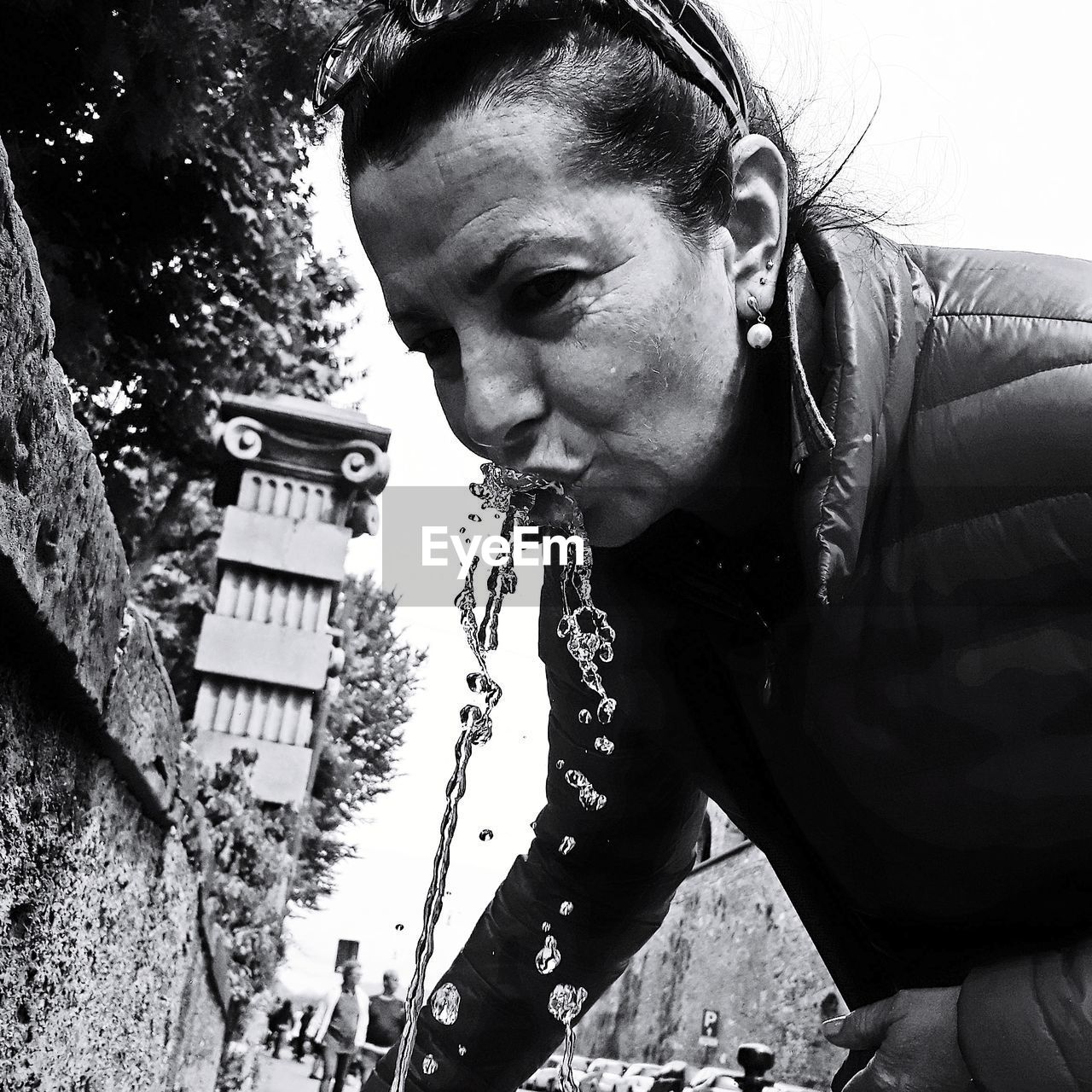 Portrait of woman drinking water from fountain in city