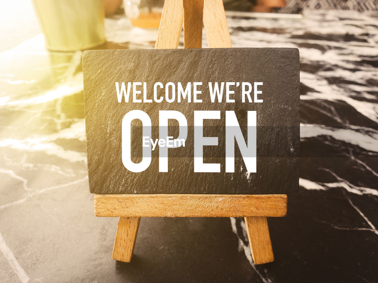 Welcome we're open written on a chalkboard,open sign broad on table cafe.