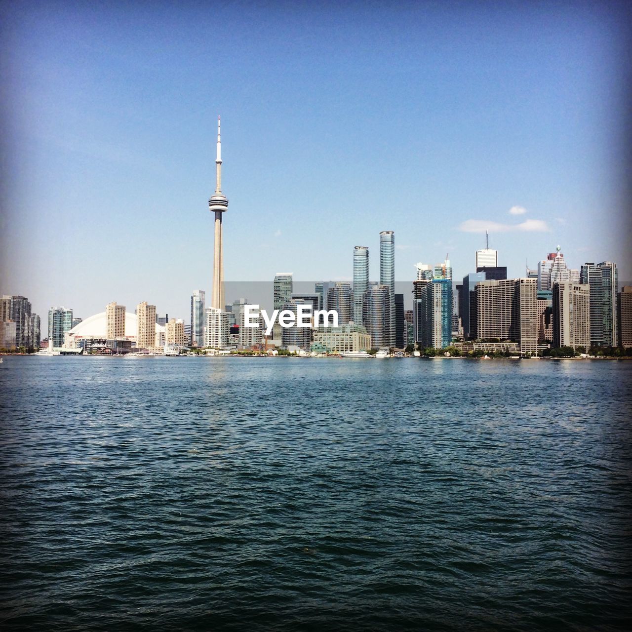 Sea against cn tower amidst modern buildings in city