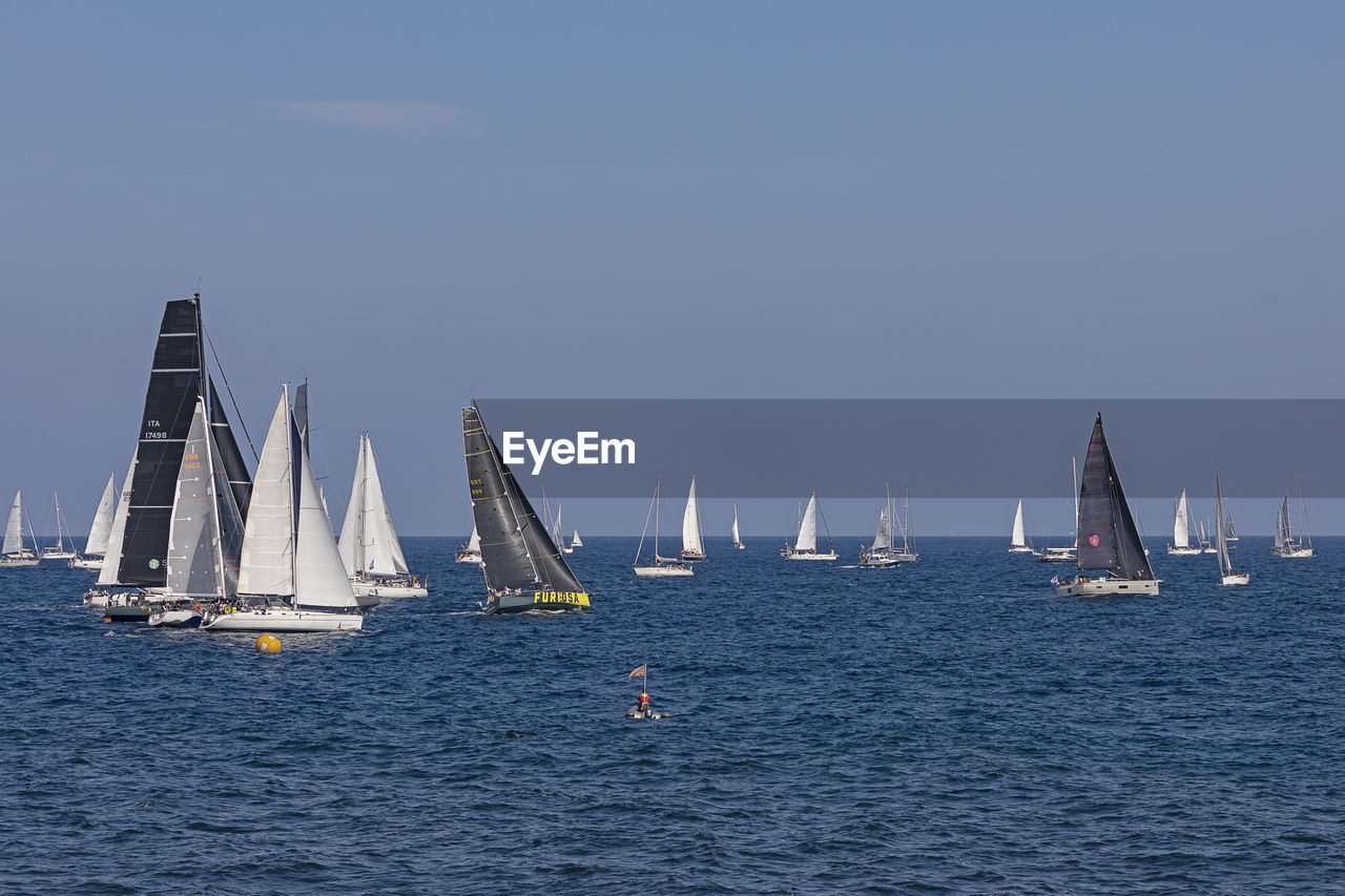 SAILBOATS IN SEA AGAINST CLEAR SKY