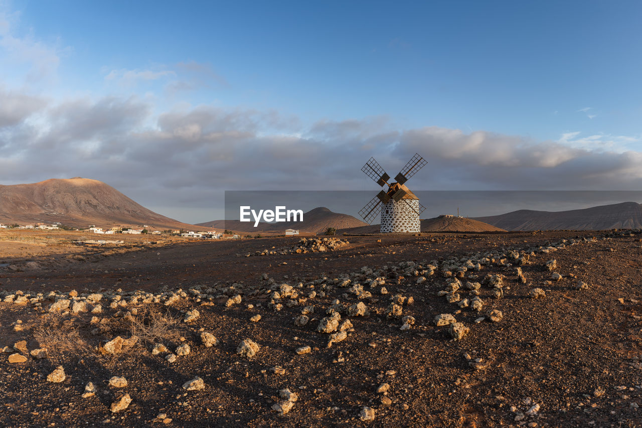 Traditional spanish white stone windmill volcanic rocky sunset landscape 