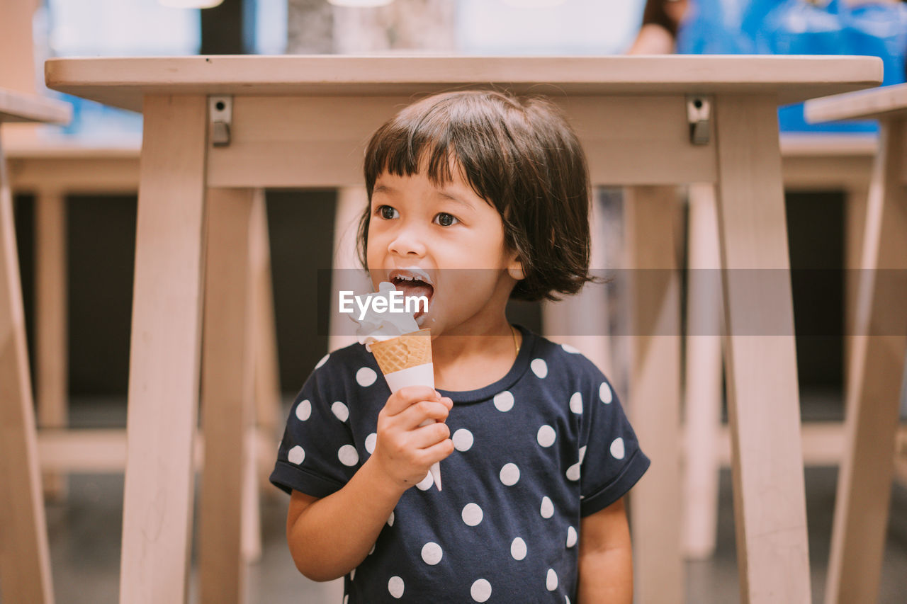 Cute girl licking ice cream while looking away