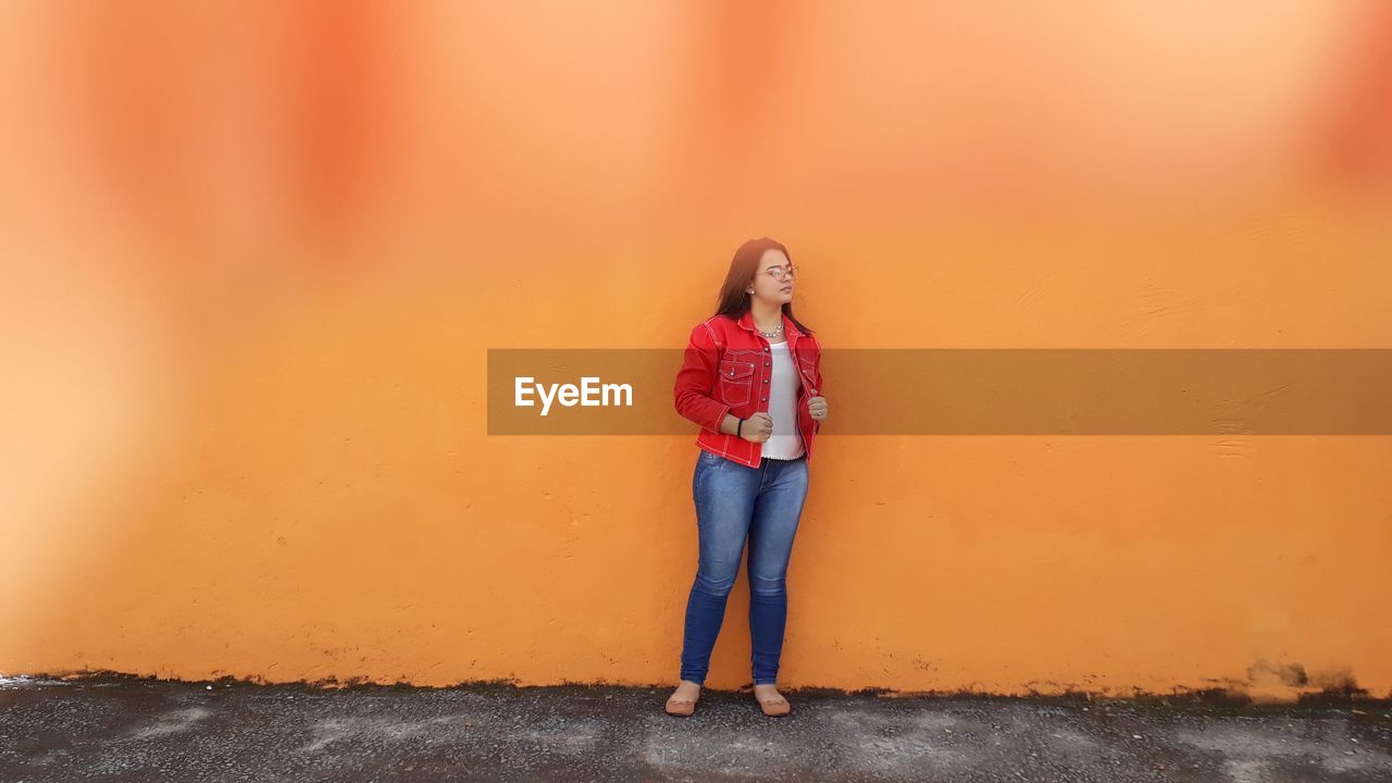 Woman standing against orange wall