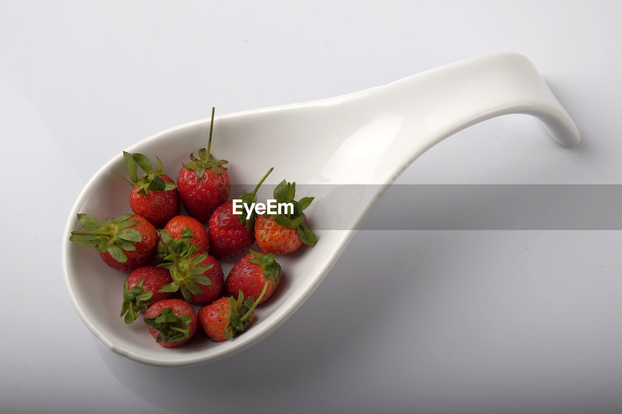 Close-up of strawberries in spoon on white background