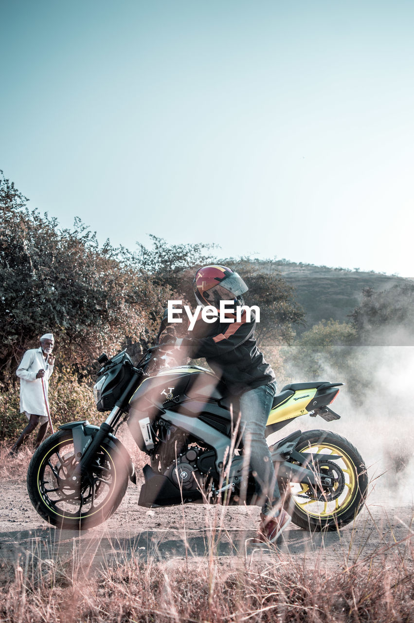 MAN RIDING MOTORCYCLE ON FARM