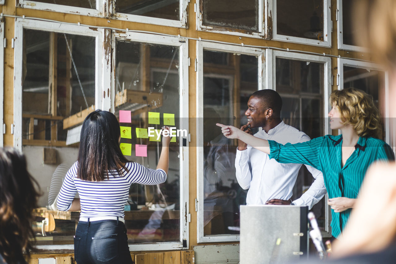 Confident computer programmers using adhesive notes to pen down their innovative ideas during meeting at workplace