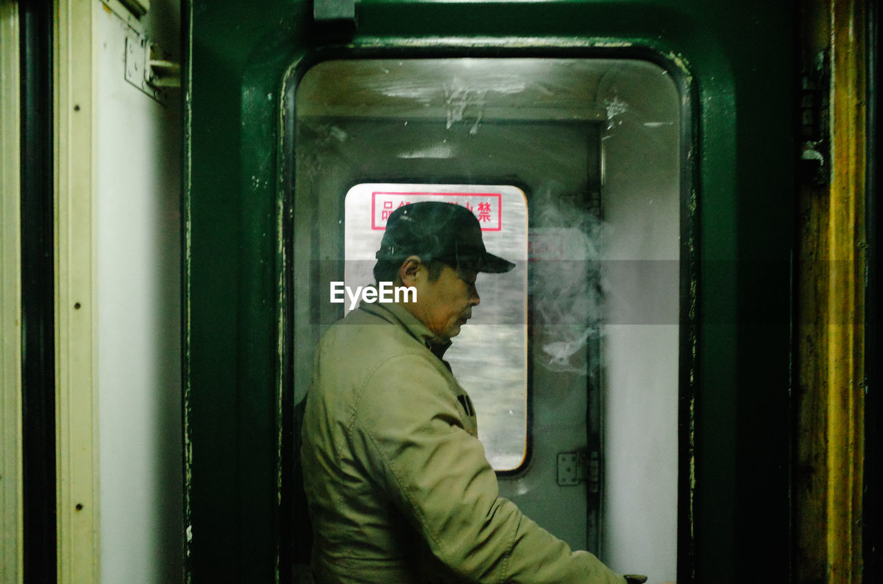 SIDE VIEW OF MAN LOOKING THROUGH TRAIN