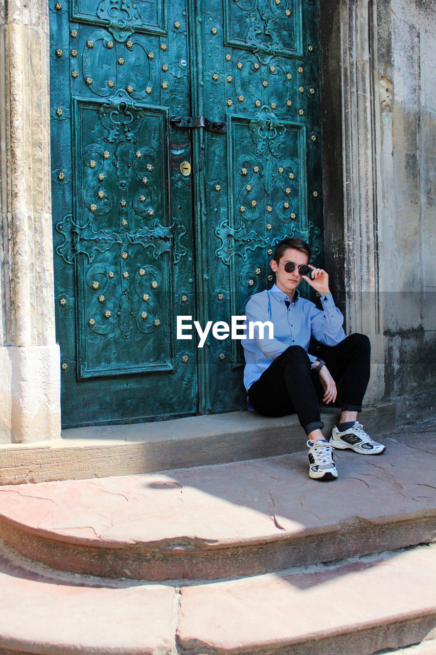 Full length of young man sitting at entrance