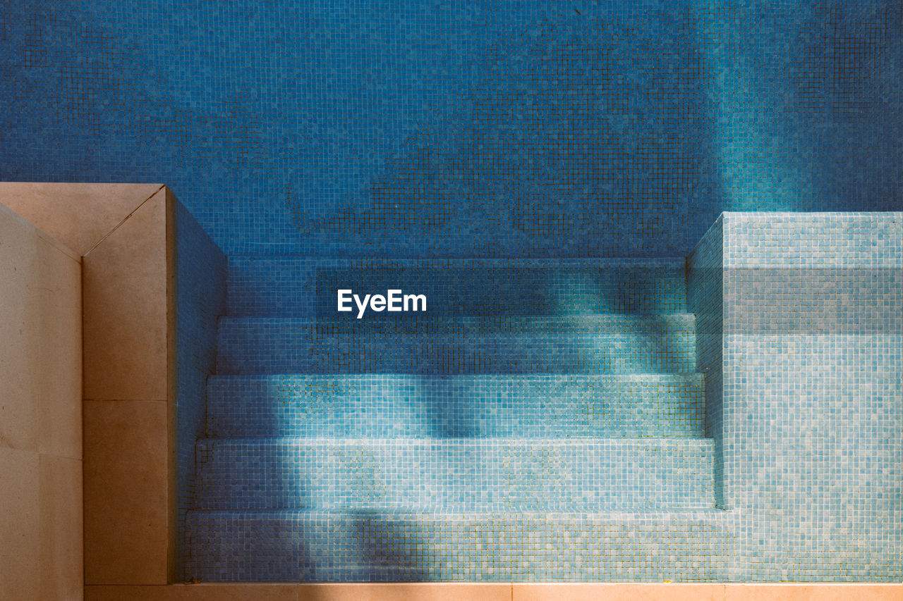 Top view of tiled bottom and steps in swimming pool with clean blue water