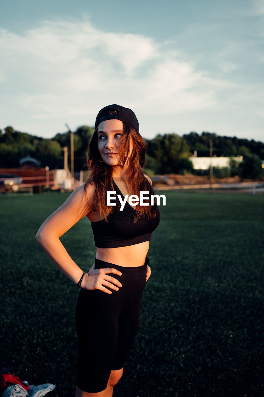 Portrait of young woman standing against sky