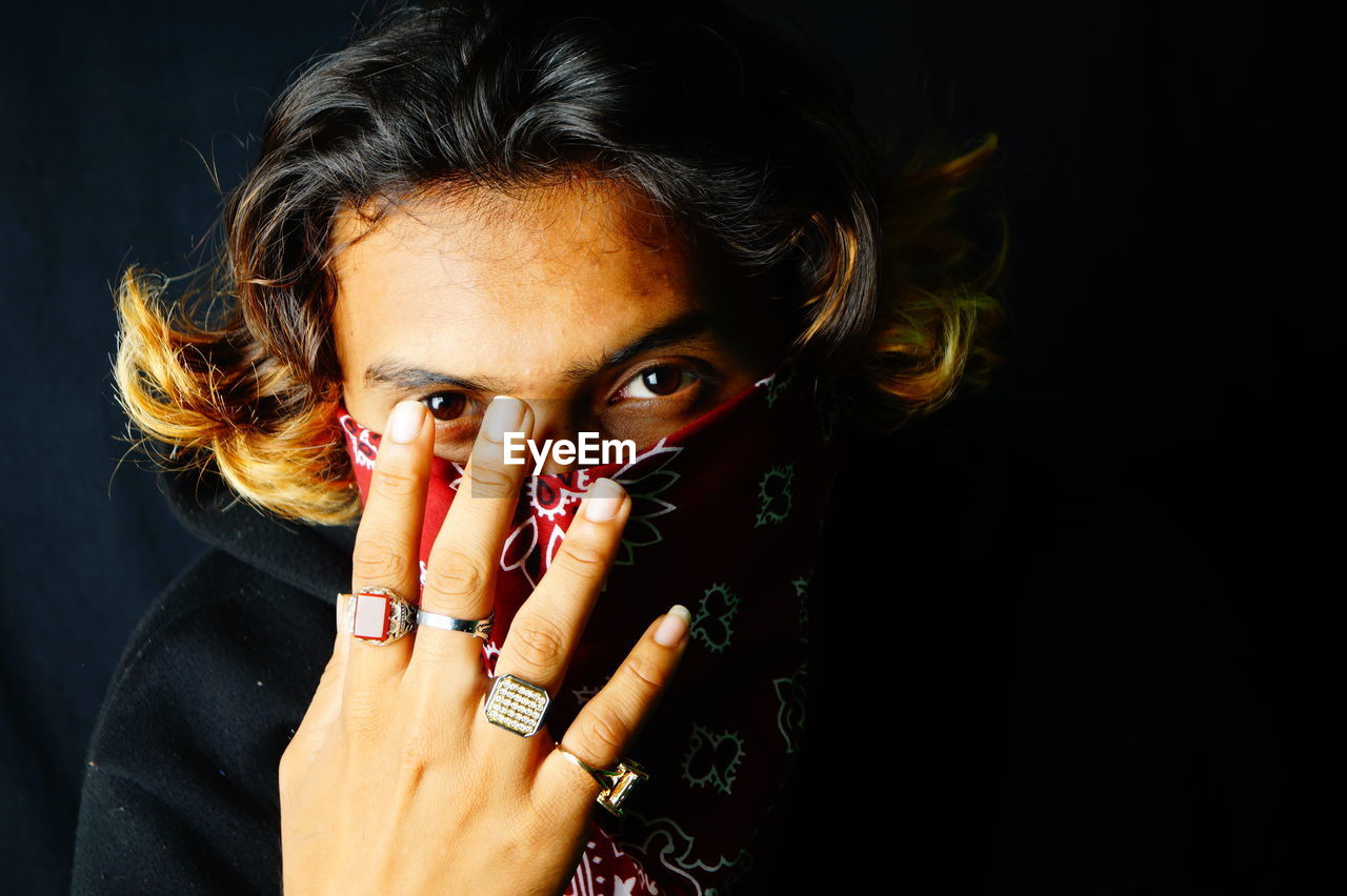 Portrait of woman covering face against black background