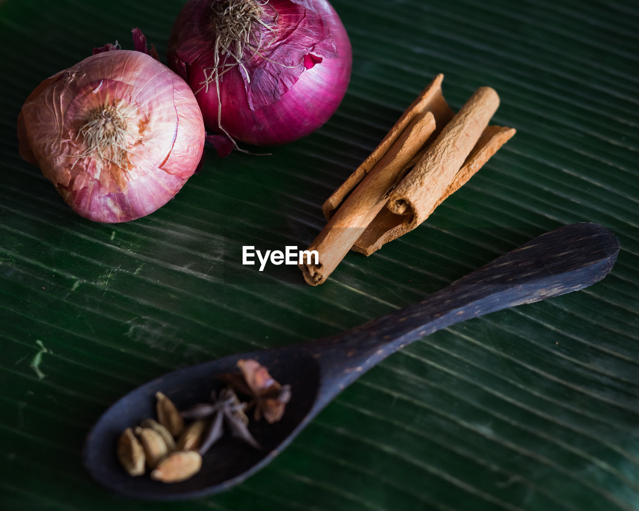 Cooking spices on banana leaf. cardamom, star anise, cinnamon and onions.