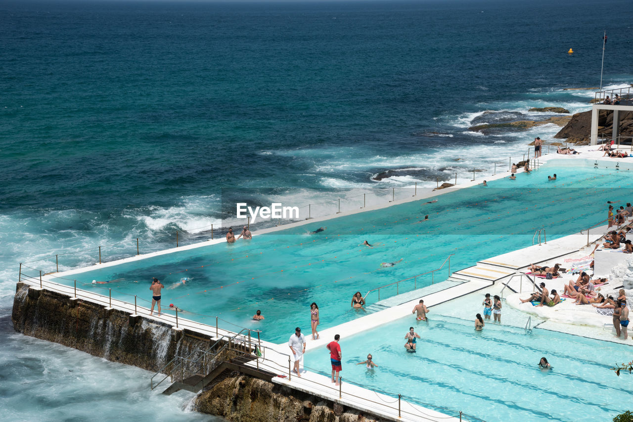 HIGH ANGLE VIEW OF PEOPLE SWIMMING IN POOL