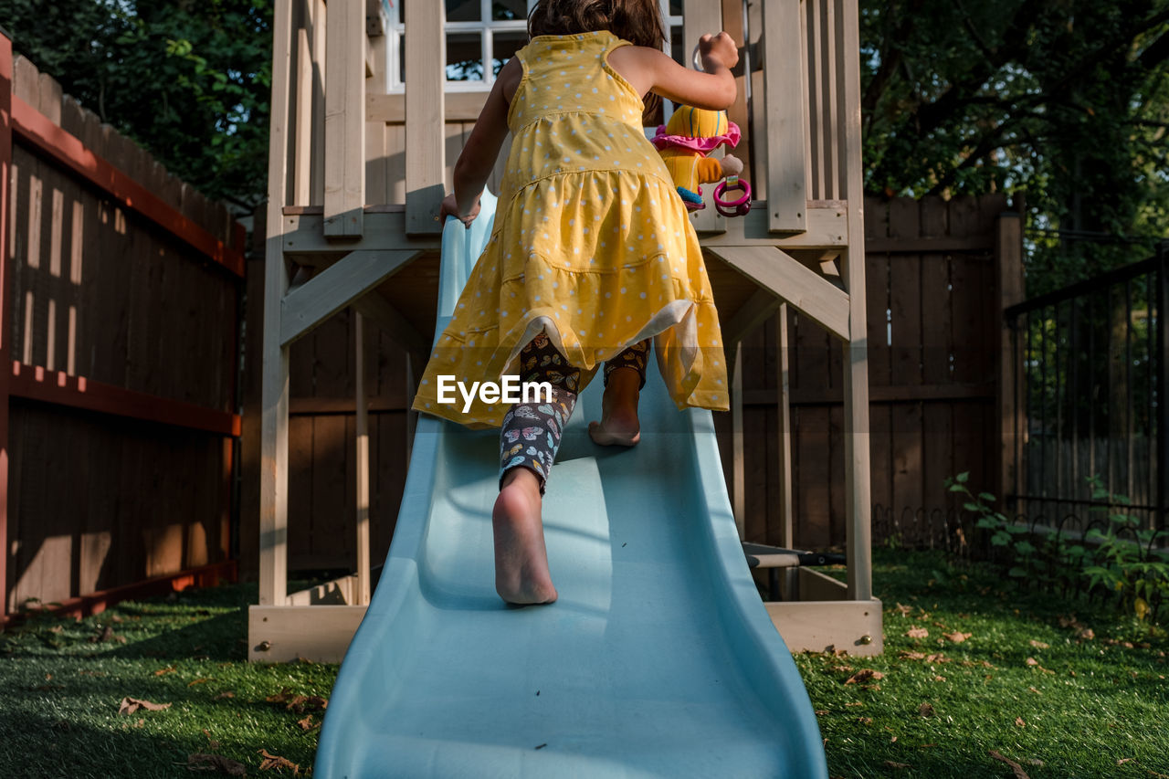 Little girl climbing up a slide in backyard