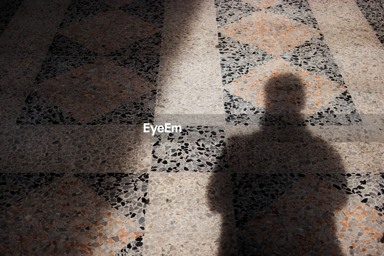 High angle view of person shadow on tiled floor