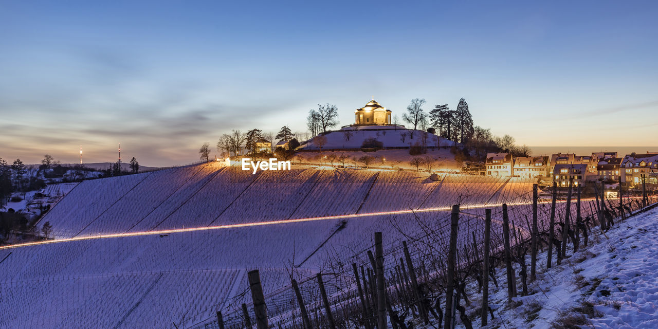 Germany, baden-wurttemberg, stuttgart, panorama of bare snow-covered vineyard at dusk with wurttemberg mausoleum in background