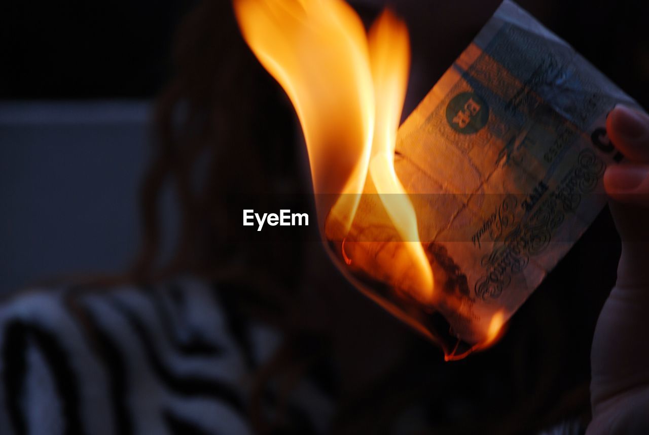 Cropped image of woman burning paper currency