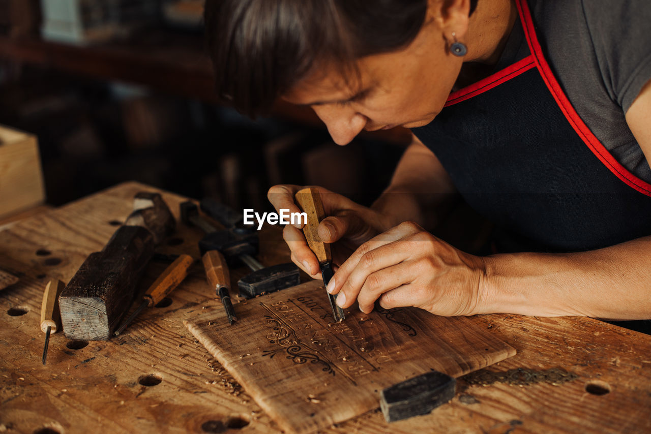 Woman engraving wooden panel using hand tools