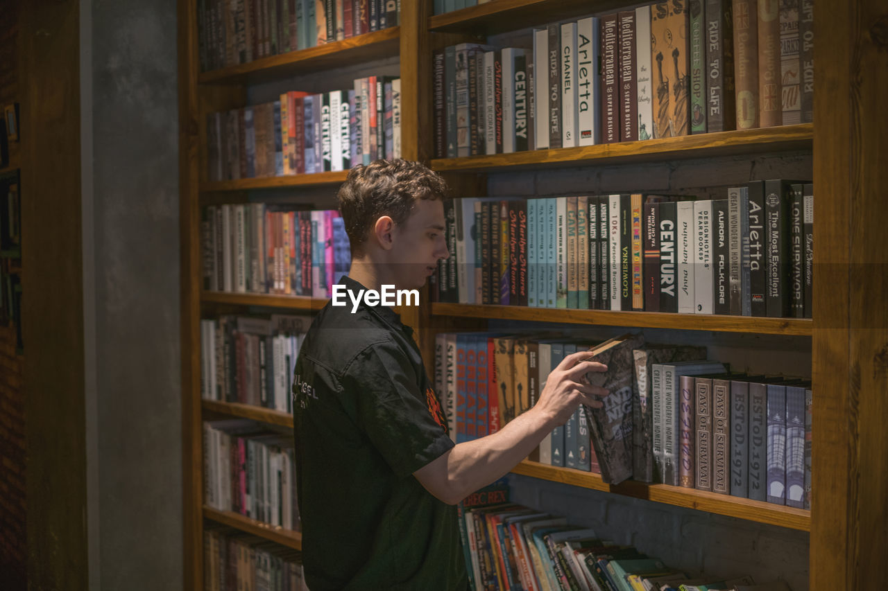 Young man reading book at library