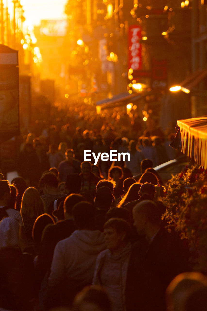 Crowd on street in city at sunset