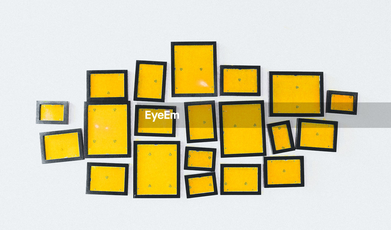 Close-up of yellow picture frames over white background