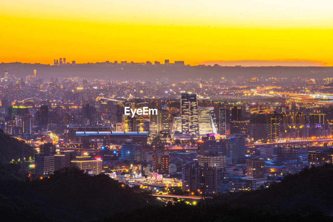 High angle view of illuminated city against sky at sunset