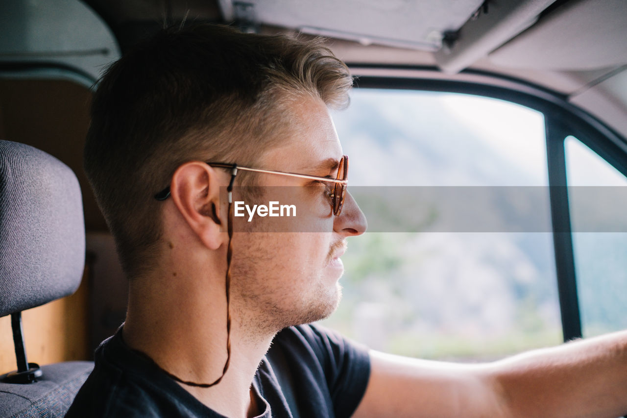 Profile view of young man wearing sunglasses while driving car