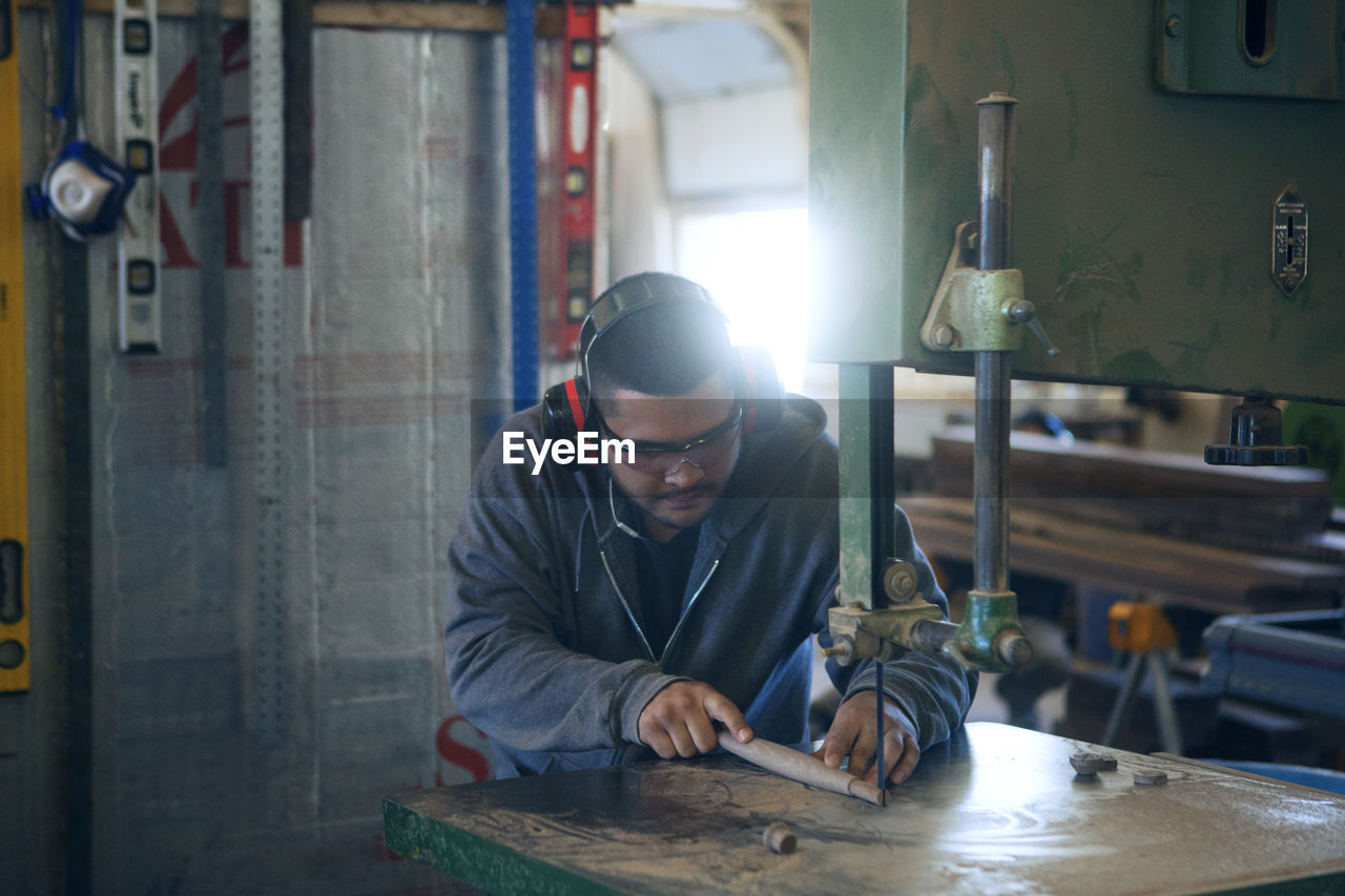 Male carpenter using machinery while working at workshop