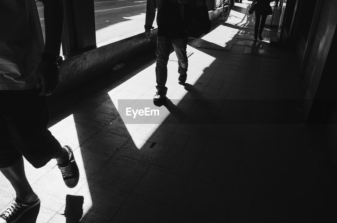 LOW SECTION OF PEOPLE STANDING ON FLOOR IN CORRIDOR