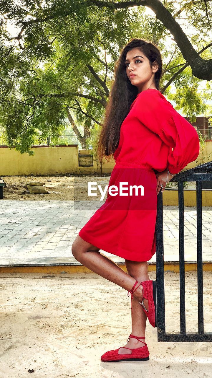 Young woman in red dress standing outdoors