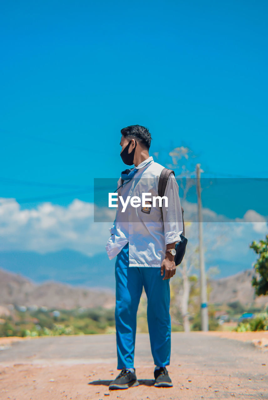 Full length of man standing against blue sky