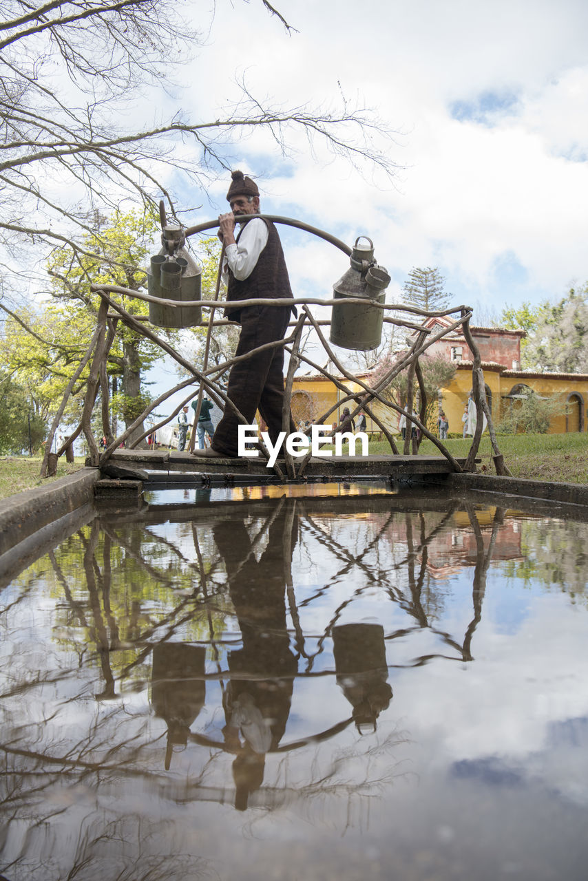 REFLECTION OF MAN STANDING ON WATER AGAINST SKY