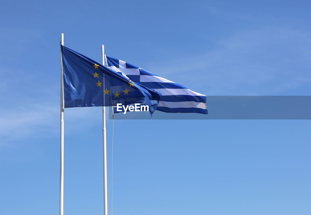 Low angle view of flags against blue sky