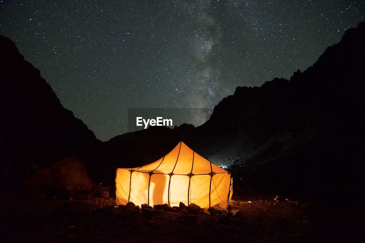 Illuminated tent on land against star field at night