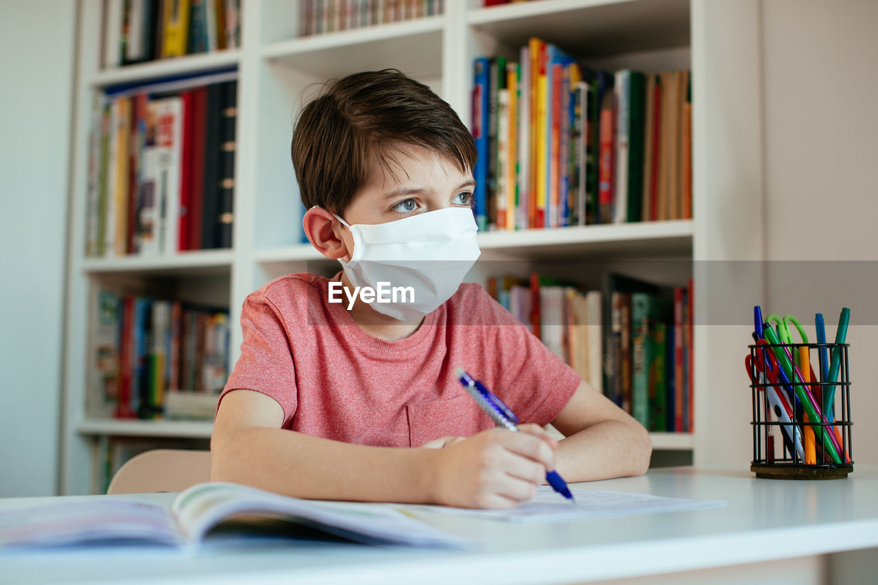 Boys wearing flu mask while studying at home