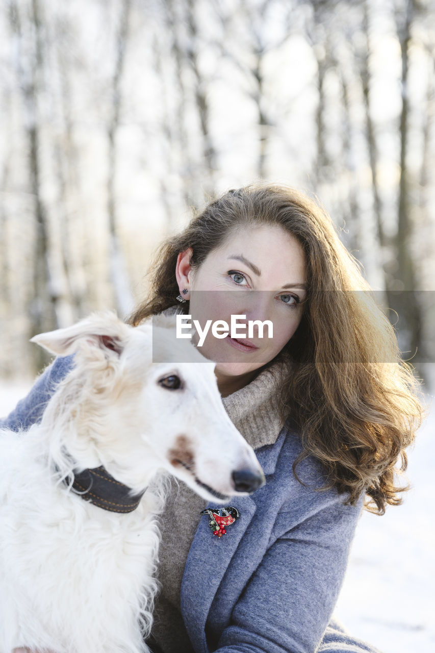 Mature woman with white greyhound dog at winter park