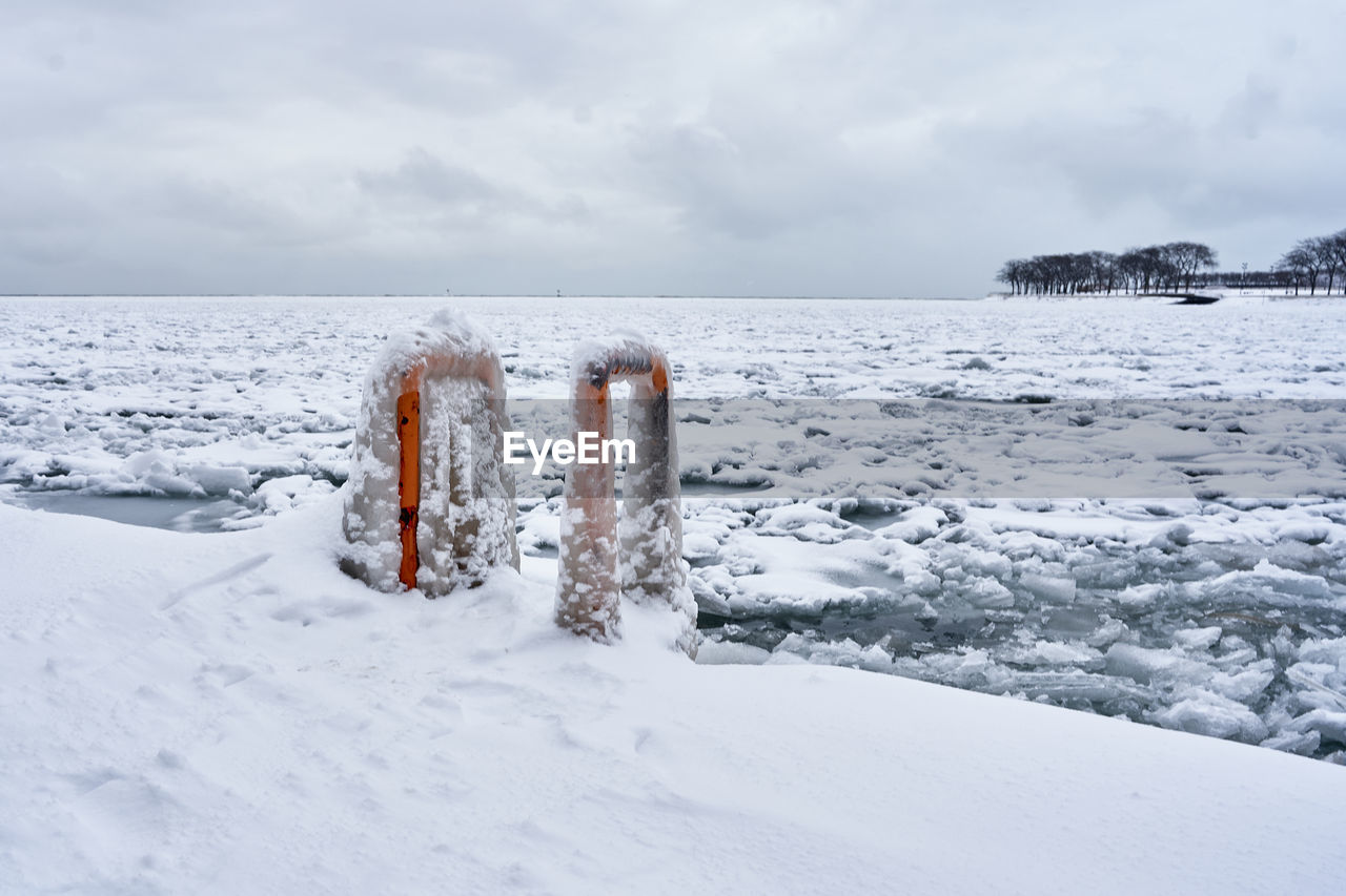 Painted metal swimmers ladder on frozen lake michigan against sky