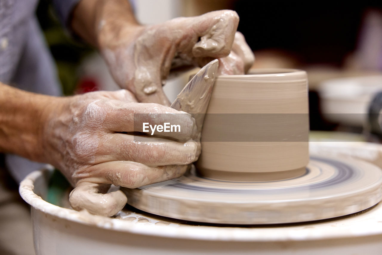 cropped hands of man making pottery at workshop