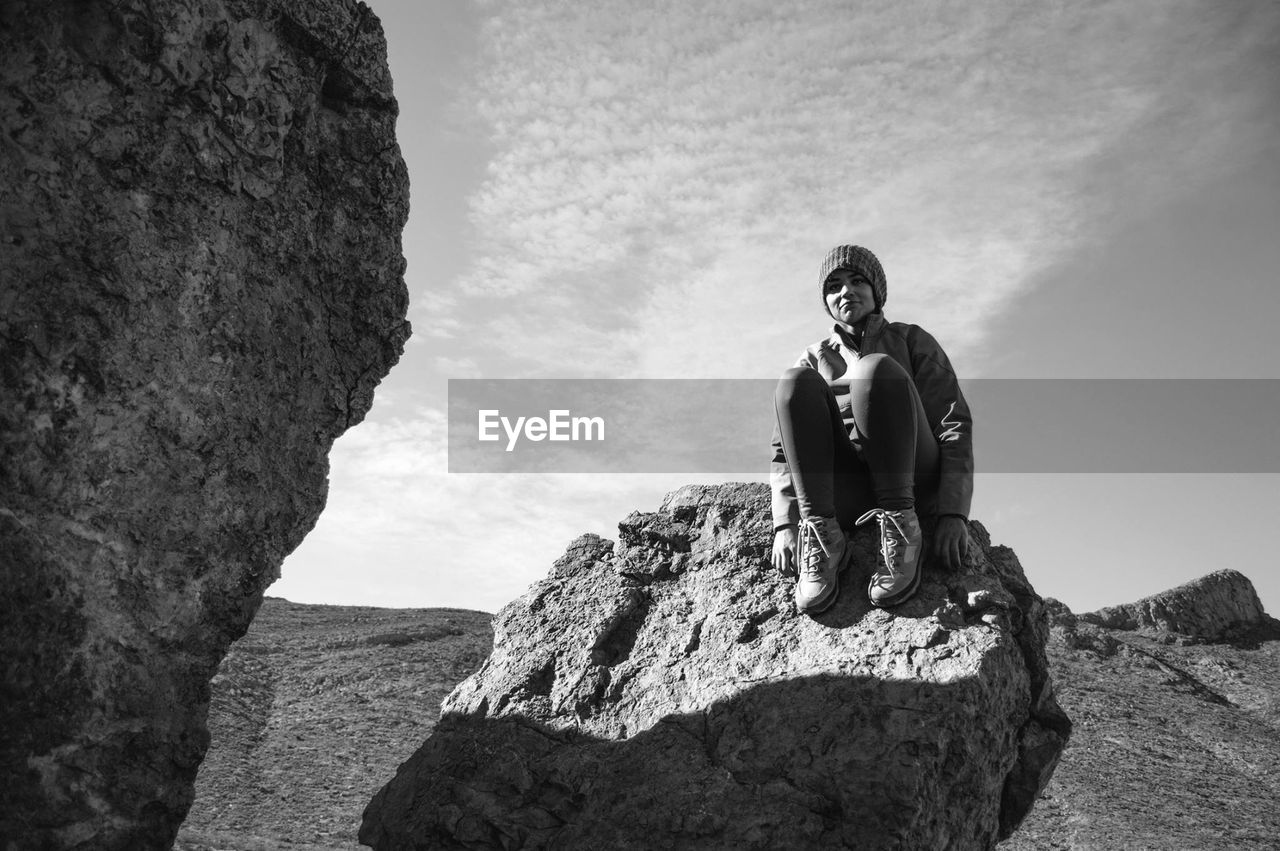 Low angle view of woman sitting on rock