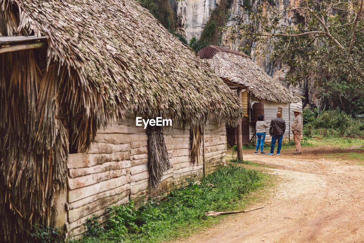 PEOPLE WALKING OUTSIDE HOUSE AMIDST TREES