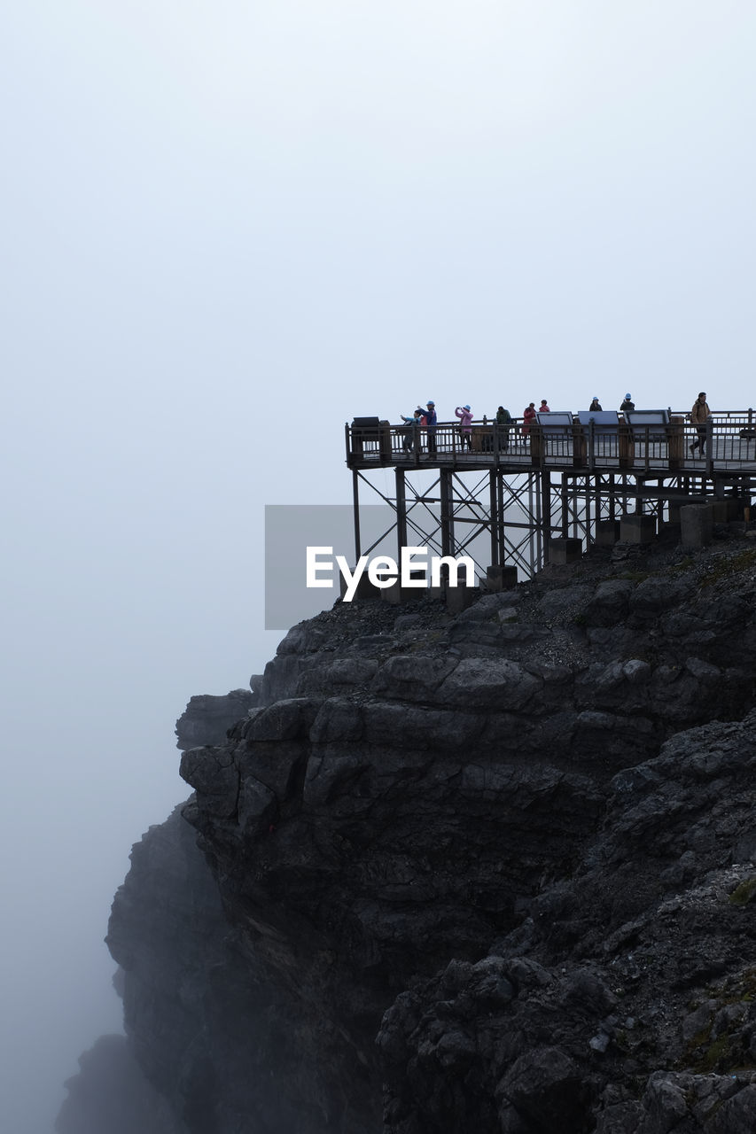 People at observation point on cliff during foggy weather