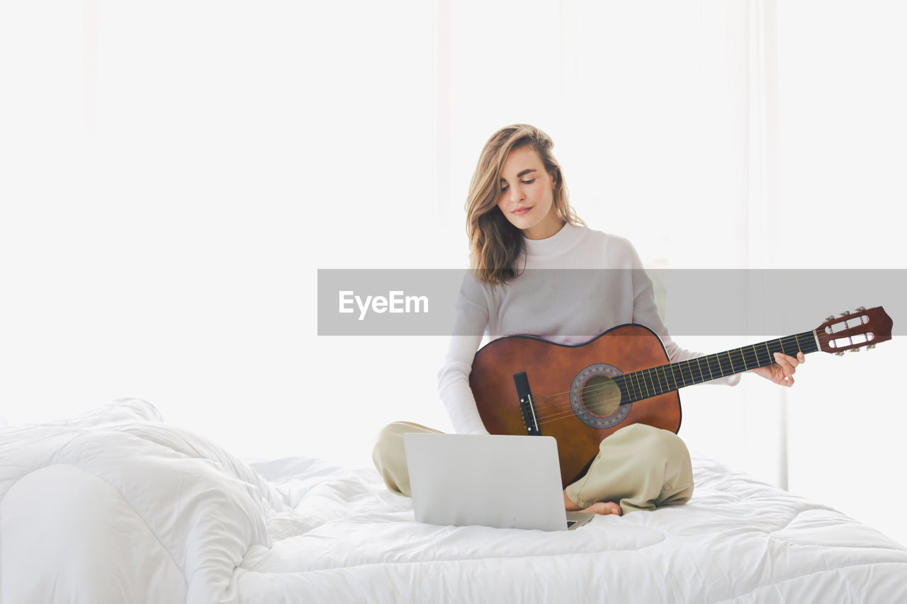 YOUNG WOMAN PLAYING GUITAR AT HOME