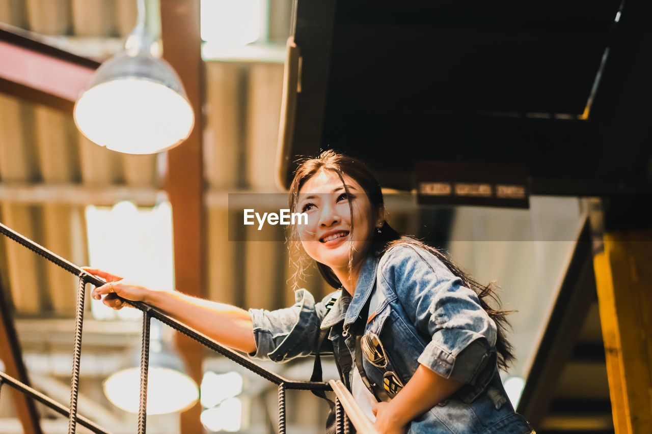 Smiling woman standing under illuminated pendant light