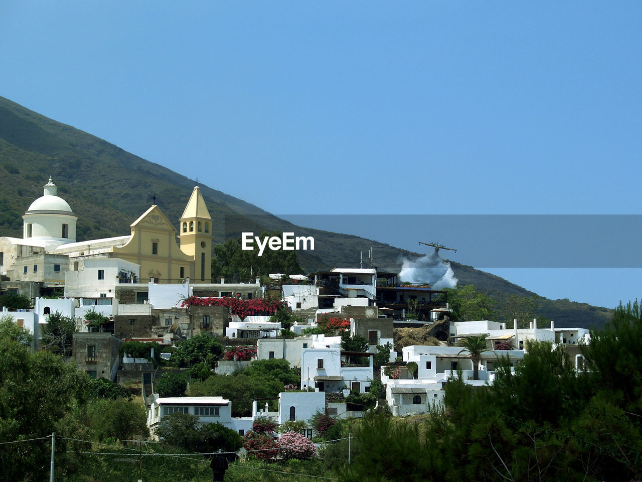 Aircraft over houses against clear sky at aeolian islands