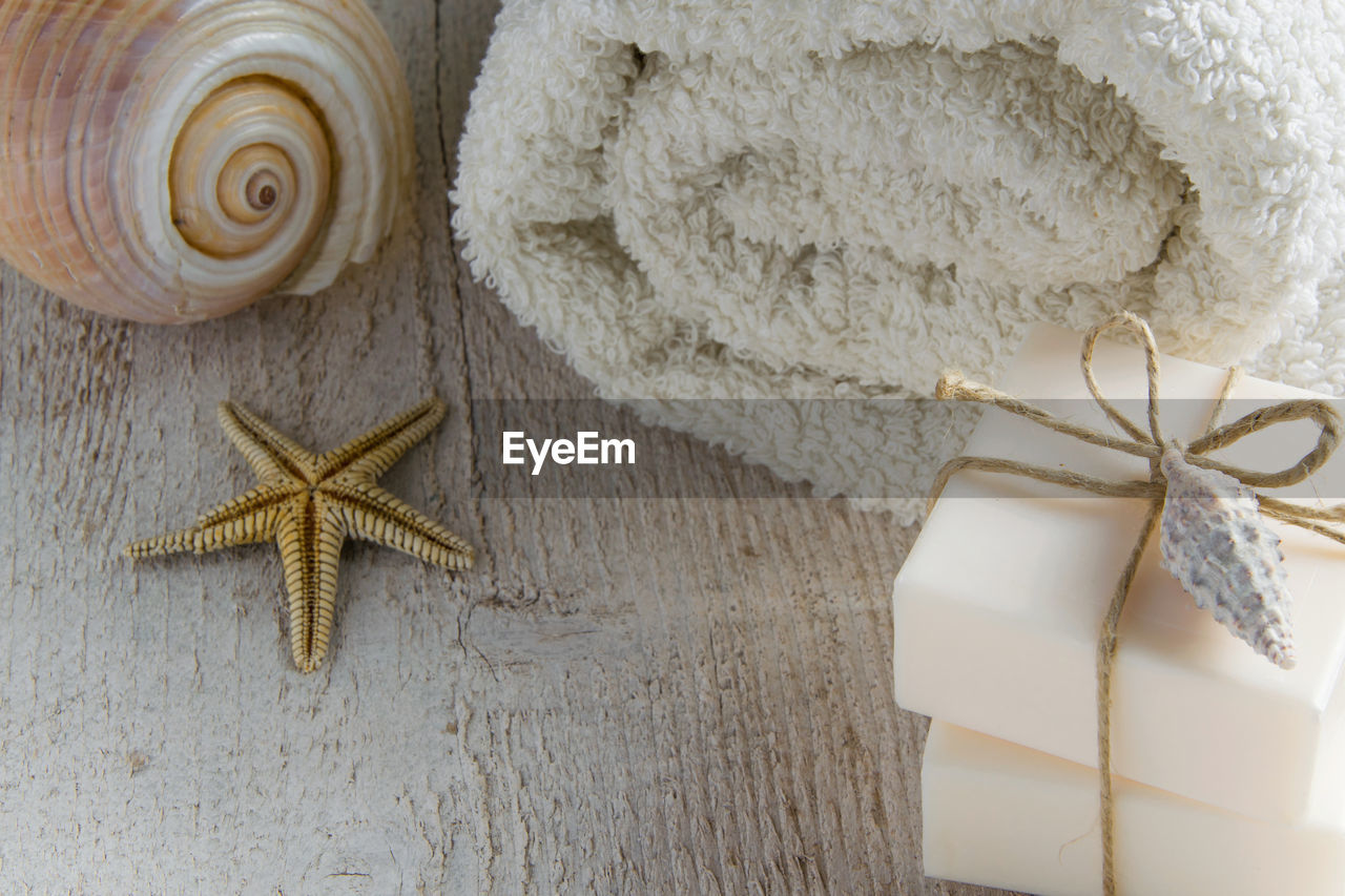 High angle view of soap bars with rolled up towel and starfish on wooden table