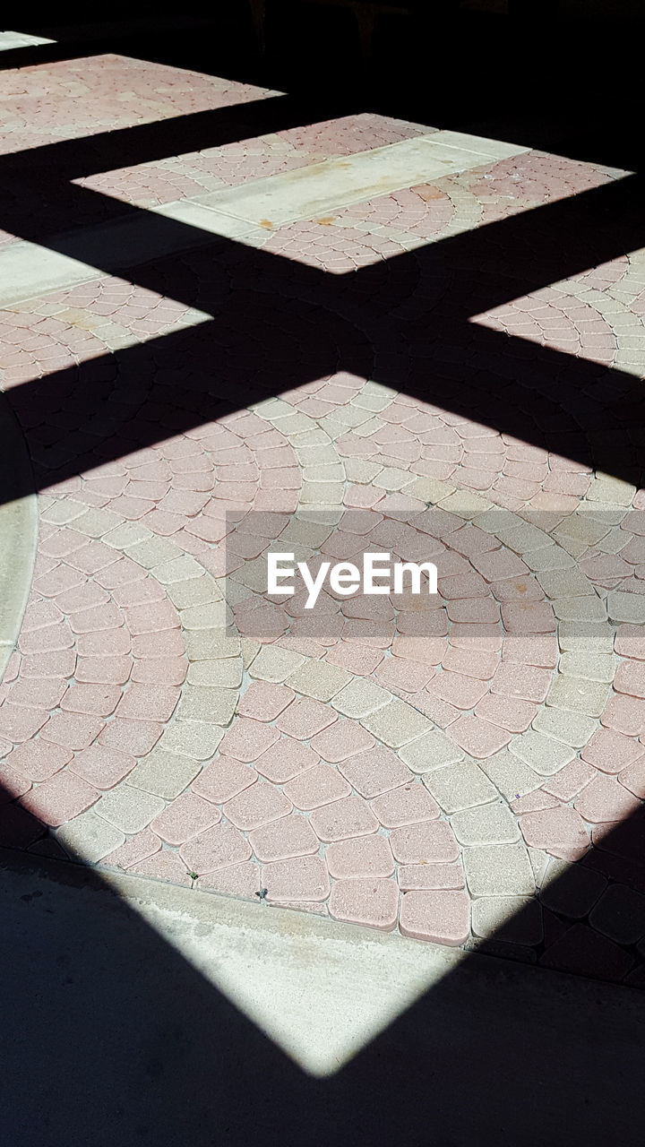 HIGH ANGLE VIEW OF TILED FLOOR WITH SHADOW ON FOOTPATH