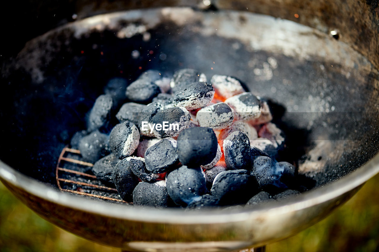 Closeup of glowing coal in metal grill on summer day in the garden