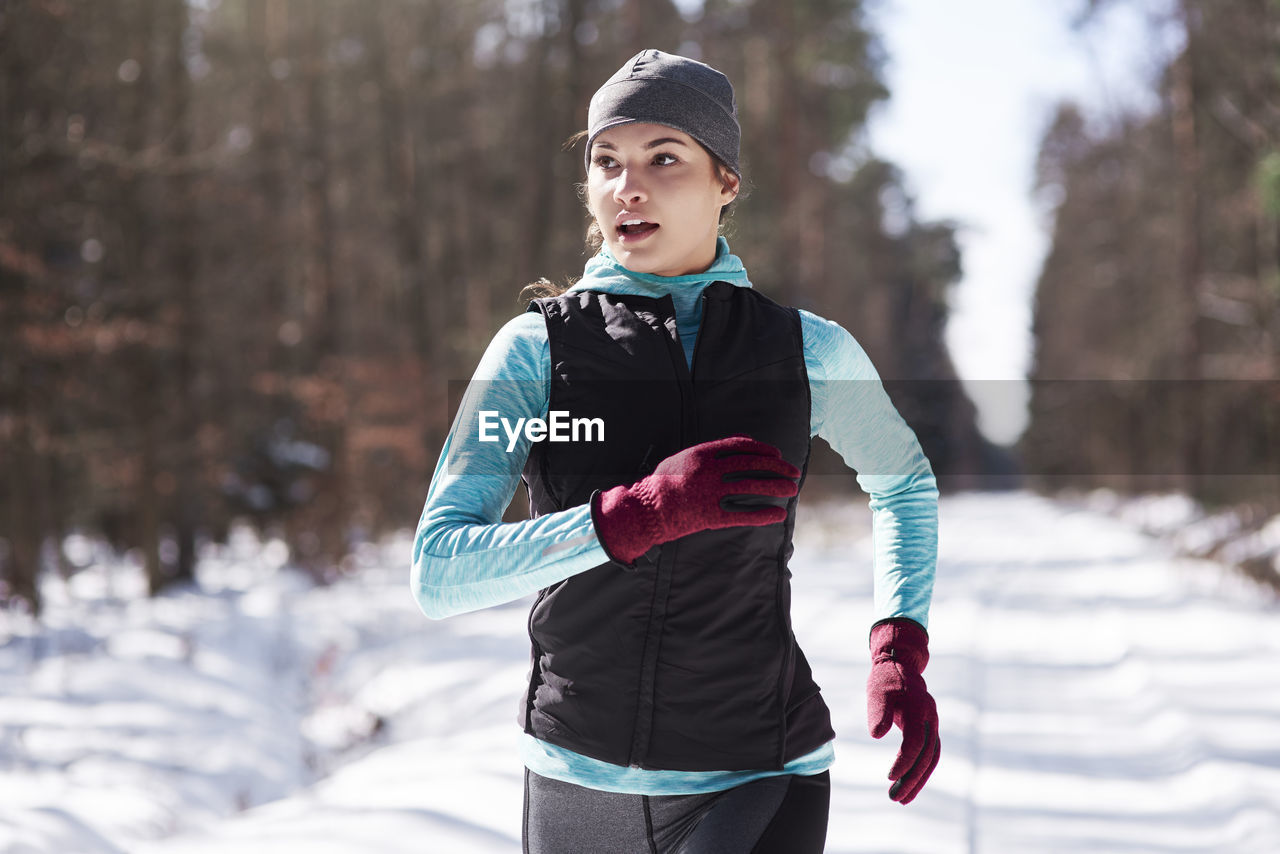 Portrait of young woman jogging in winter forest