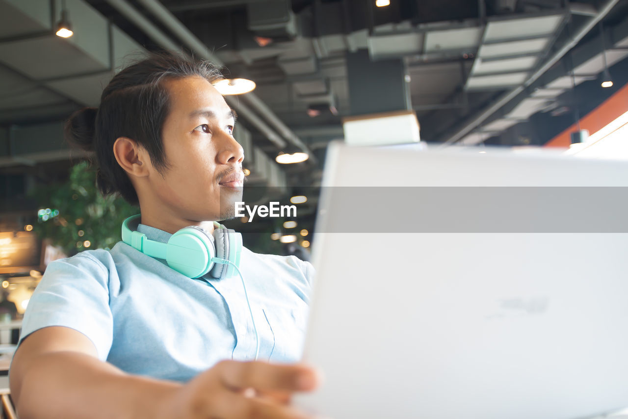 Businessman wearing headphones while sitting in cafe